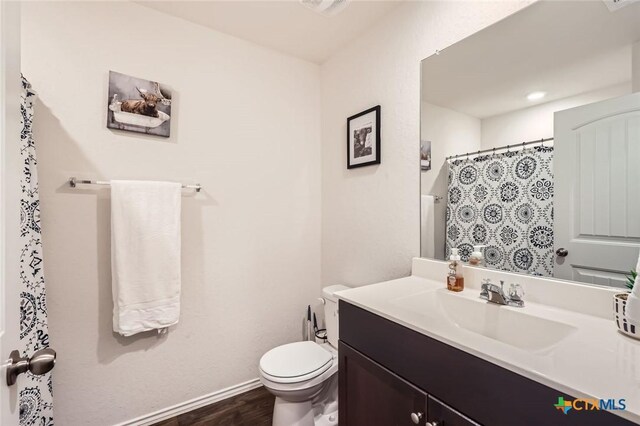 full bathroom featuring toilet, wood finished floors, a shower with shower curtain, baseboards, and vanity