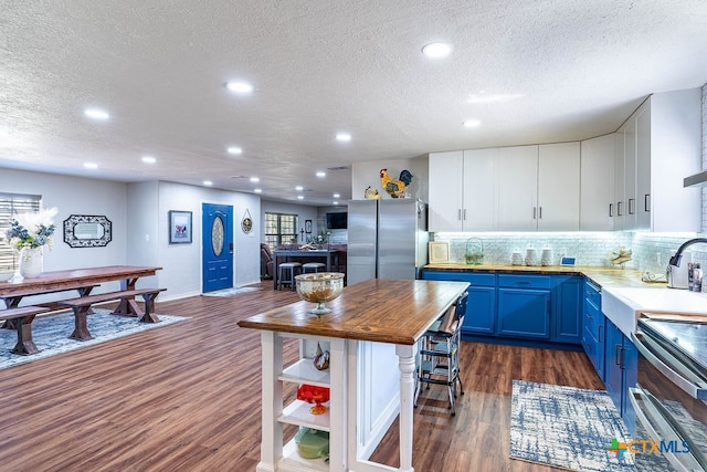 kitchen with dark wood-type flooring, appliances with stainless steel finishes, blue cabinets, and white cabinets