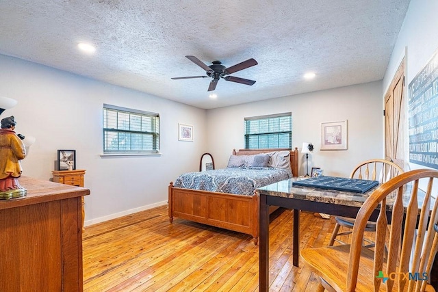 bedroom with multiple windows, light hardwood / wood-style floors, and a textured ceiling