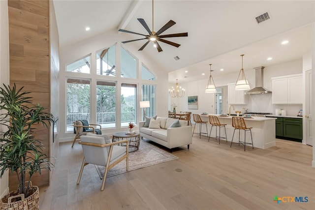 living room featuring beamed ceiling, high vaulted ceiling, light hardwood / wood-style floors, and ceiling fan with notable chandelier