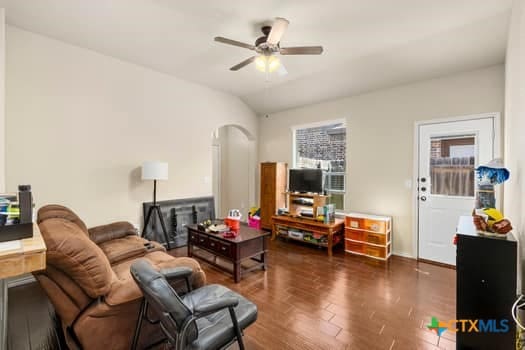 living room featuring dark wood-type flooring, ceiling fan, vaulted ceiling, and a healthy amount of sunlight