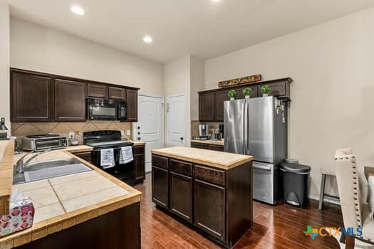 kitchen featuring black appliances, a kitchen island, sink, and dark brown cabinetry