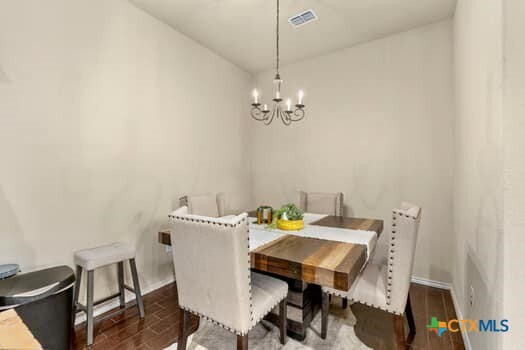 dining area with dark wood-type flooring and a notable chandelier