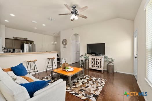 living room with ceiling fan with notable chandelier, dark hardwood / wood-style flooring, and a healthy amount of sunlight