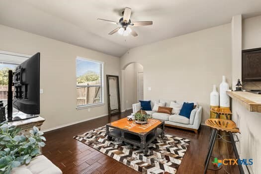 living room featuring dark wood-type flooring, ceiling fan, and vaulted ceiling