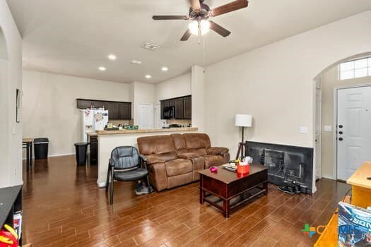 living room with dark wood-type flooring and ceiling fan