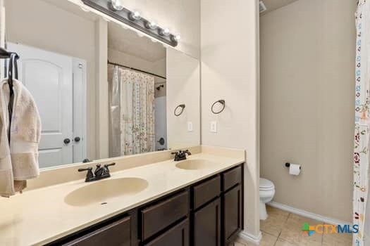 bathroom with toilet, vanity, and tile patterned floors