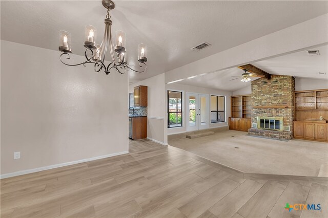 unfurnished living room featuring a fireplace, ceiling fan with notable chandelier, vaulted ceiling with beams, and light hardwood / wood-style flooring