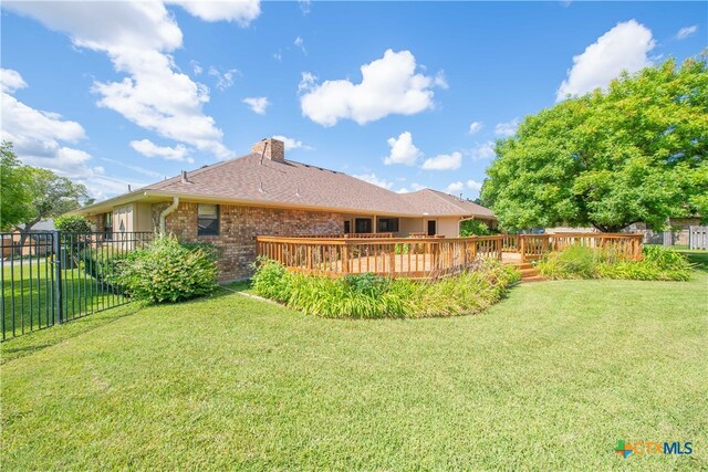 back of house featuring a lawn and a wooden deck