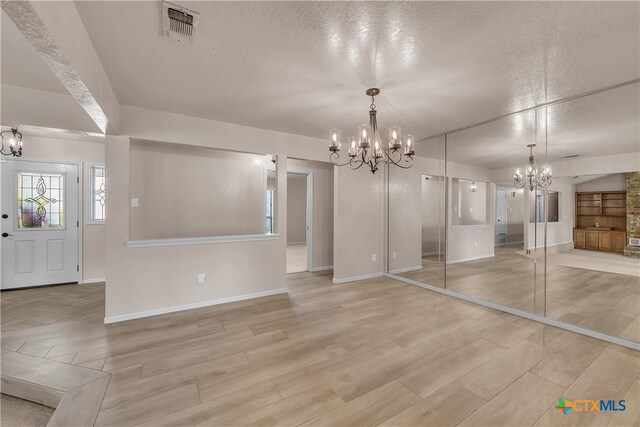 interior space with a textured ceiling, light hardwood / wood-style flooring, and a notable chandelier