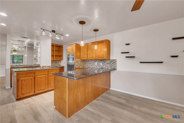 kitchen featuring hanging light fixtures, kitchen peninsula, double oven, ceiling fan, and light hardwood / wood-style flooring