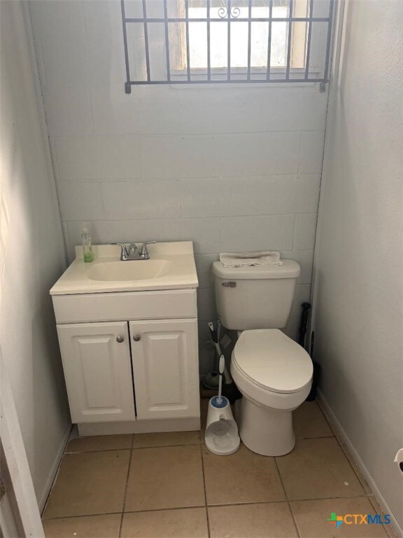 half bath with vanity, tile patterned flooring, and toilet
