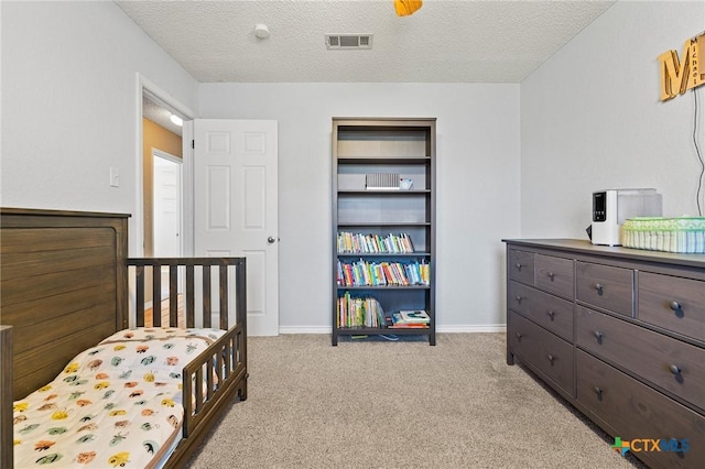 bedroom featuring visible vents, baseboards, light colored carpet, and a textured ceiling