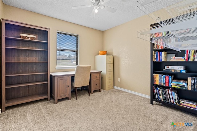 office area featuring a ceiling fan, light colored carpet, baseboards, and a textured ceiling