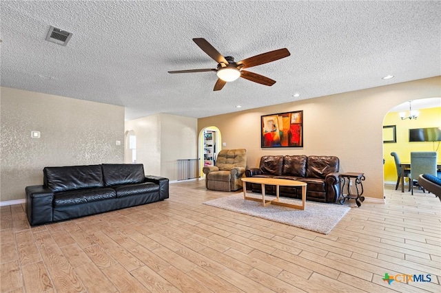 living room with arched walkways, visible vents, a textured ceiling, and wood finished floors