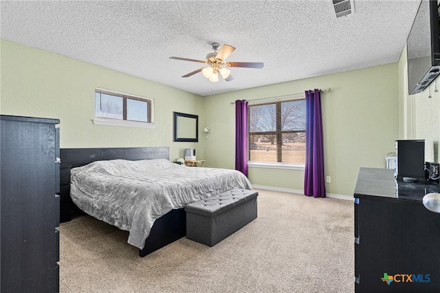 carpeted bedroom with a ceiling fan, baseboards, visible vents, and a textured ceiling