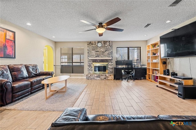 living area with visible vents, arched walkways, a textured ceiling, and wood finished floors