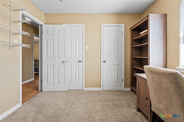 home office with baseboards, light colored carpet, and a textured ceiling