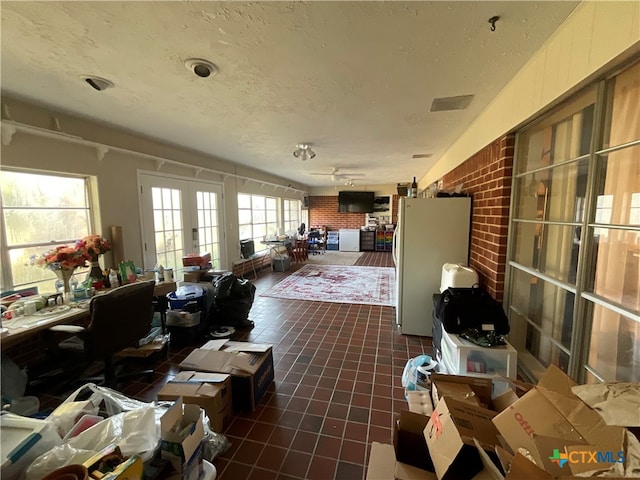 interior space with a textured ceiling, brick wall, and dark tile patterned flooring