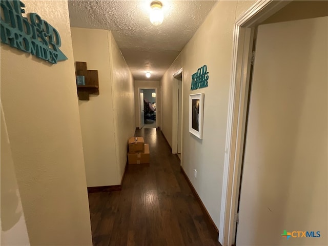 corridor featuring a textured ceiling and dark hardwood / wood-style flooring