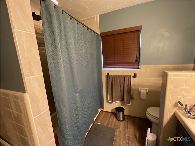 bathroom with toilet, tile walls, hardwood / wood-style floors, a textured ceiling, and a shower with shower curtain