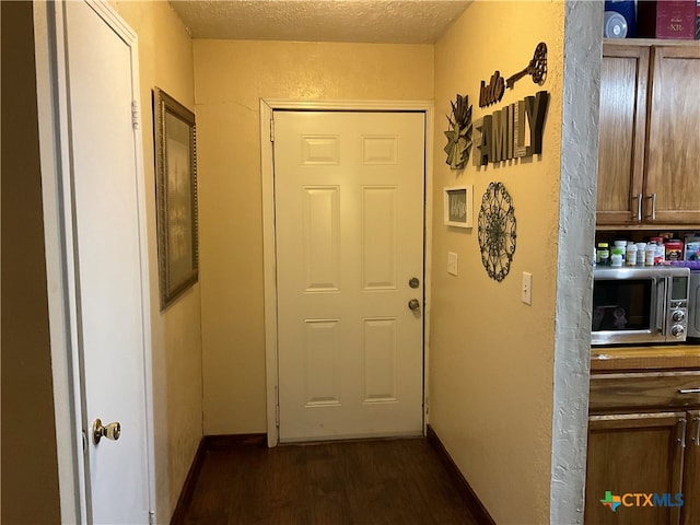 doorway with a textured ceiling and dark hardwood / wood-style floors