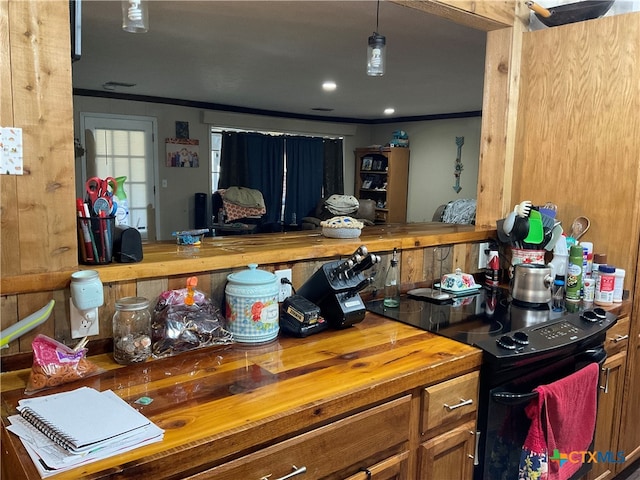 kitchen with ornamental molding, butcher block countertops, hanging light fixtures, and black range with electric stovetop