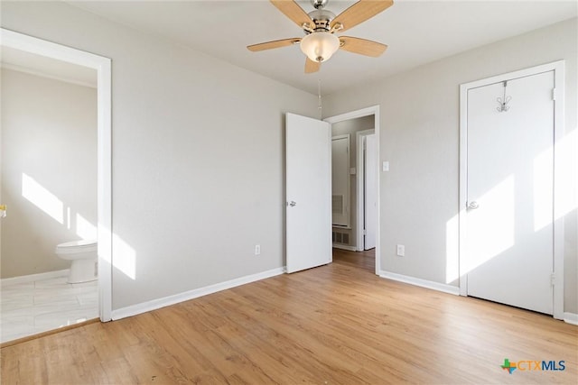 unfurnished bedroom featuring a ceiling fan, visible vents, baseboards, light wood-style flooring, and ensuite bathroom