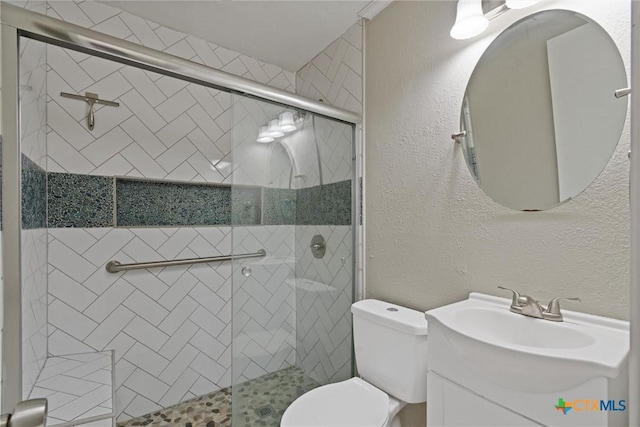 bathroom featuring toilet, a stall shower, vanity, and a textured wall