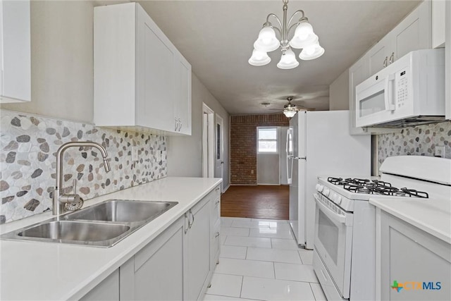 kitchen with light countertops, light tile patterned floors, white appliances, white cabinetry, and a sink