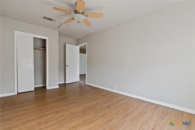 unfurnished bedroom featuring wood finished floors, visible vents, a closet, and baseboards