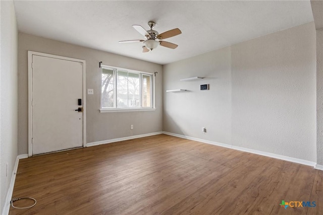 interior space with wood finished floors, a ceiling fan, and baseboards