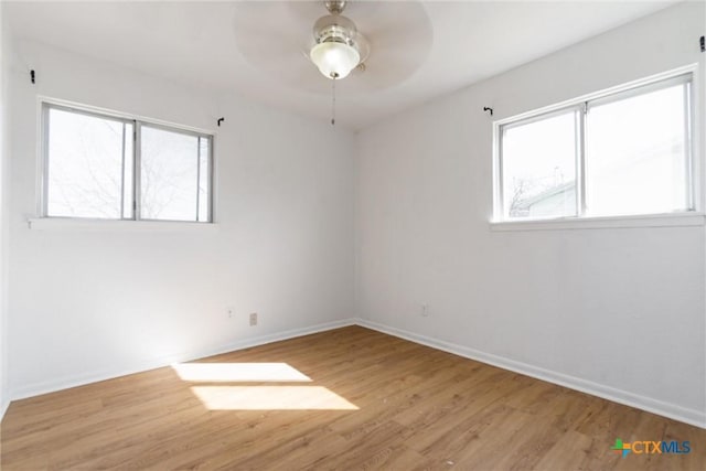 spare room featuring baseboards, wood finished floors, and a ceiling fan