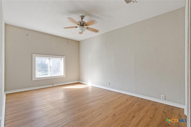 unfurnished room featuring visible vents, wood finished floors, a ceiling fan, and a textured wall