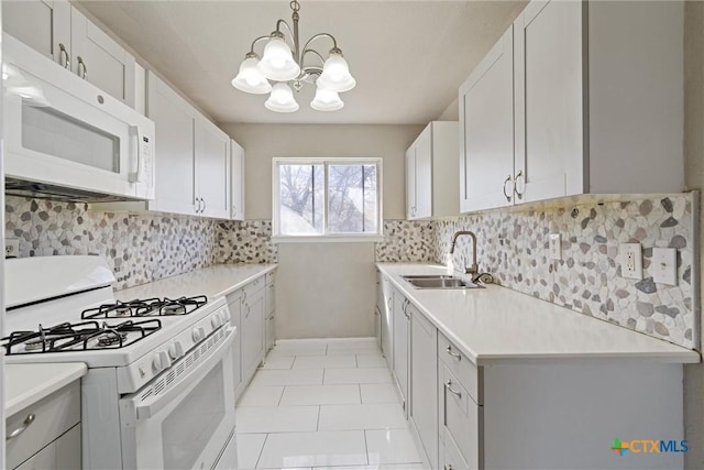 kitchen featuring white appliances, light countertops, a chandelier, and a sink