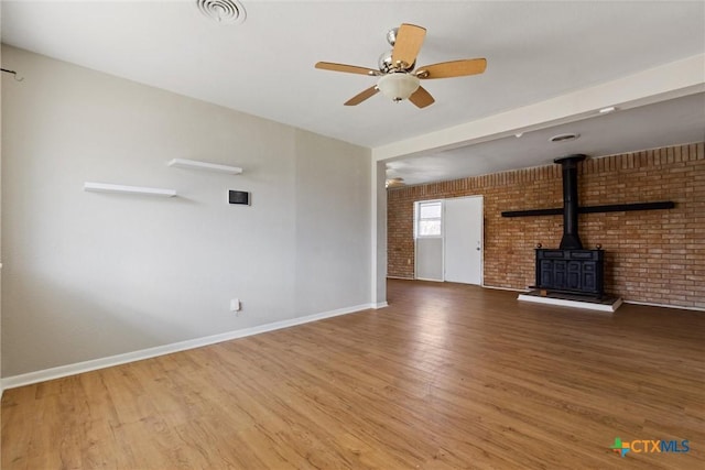 unfurnished living room with visible vents, brick wall, a ceiling fan, and wood finished floors