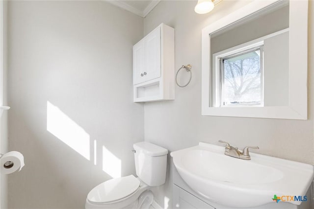 bathroom with vanity, toilet, and ornamental molding