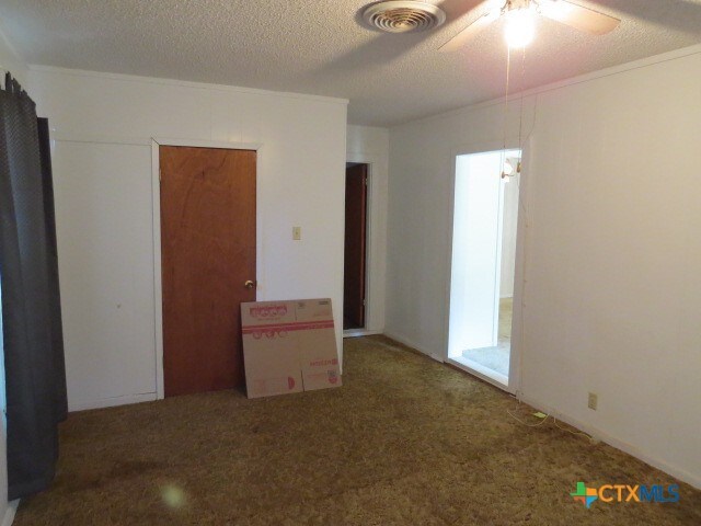 unfurnished bedroom featuring ceiling fan, a textured ceiling, and carpet floors