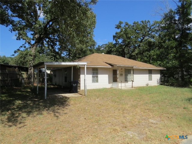 rear view of property featuring a lawn and a carport