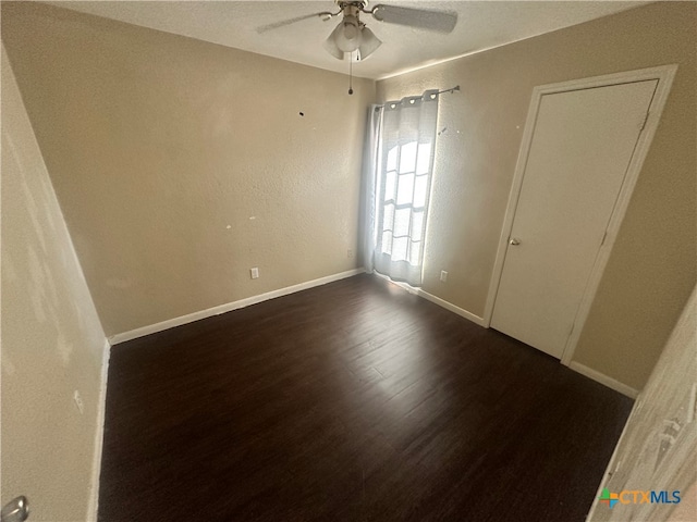 spare room featuring dark wood-type flooring and ceiling fan