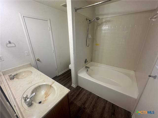 full bathroom featuring hardwood / wood-style floors, tiled shower / bath, toilet, and vanity