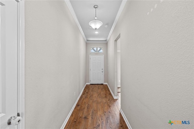 doorway with crown molding, baseboards, and wood finished floors