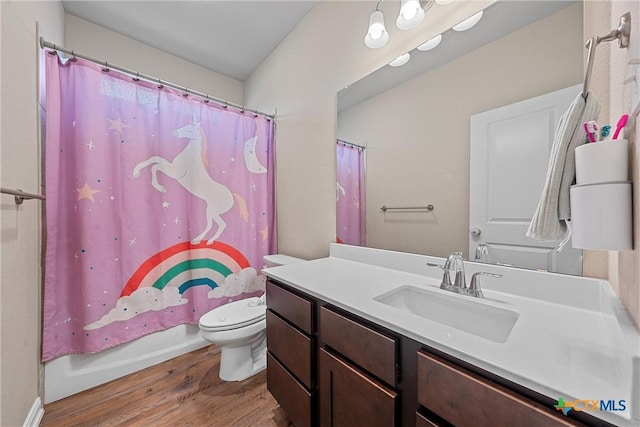 bathroom featuring wood finished floors, toilet, vanity, and shower / tub combo