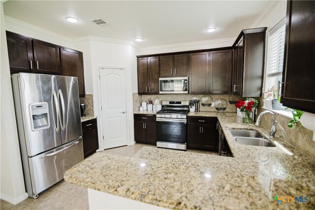 201 Boulder Ridge Dr, Cuero, TX 77954 - kitchen with appliances with stainless steel finishes, a sink, dark brown cabinets, light tile patterned flooring, and crown molding