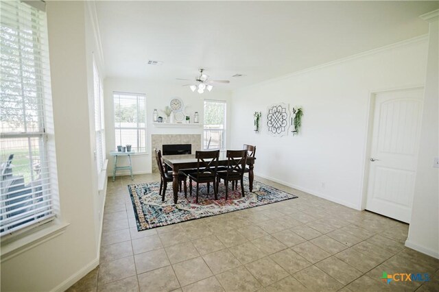 201 Boulder Ridge Dr, Cuero, TX 77954 - dining space featuring a ceiling fan, light tile patterned floors, ornamental molding, baseboards, and a tiled fireplace