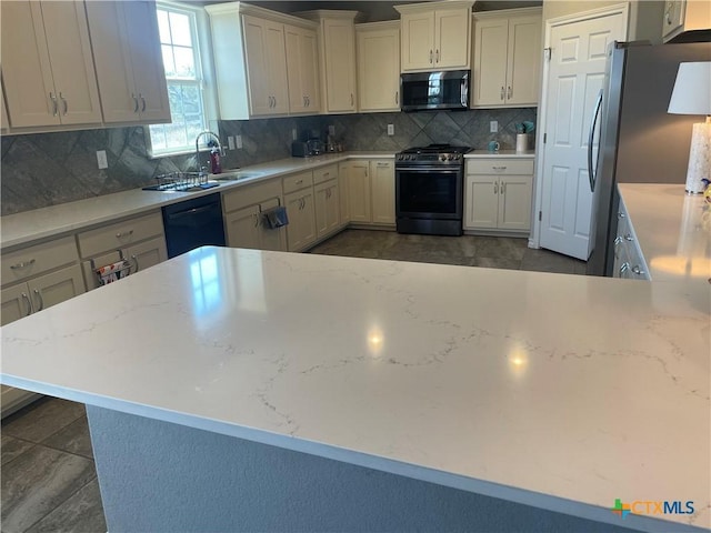 kitchen featuring tasteful backsplash, appliances with stainless steel finishes, light stone countertops, and sink