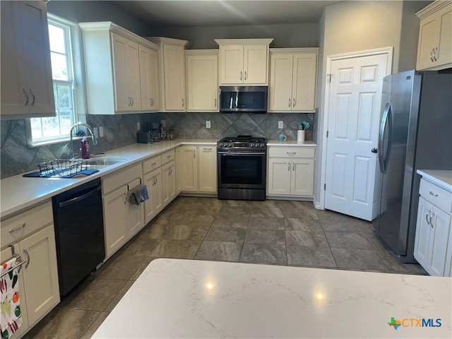 kitchen with white cabinets, appliances with stainless steel finishes, sink, and backsplash