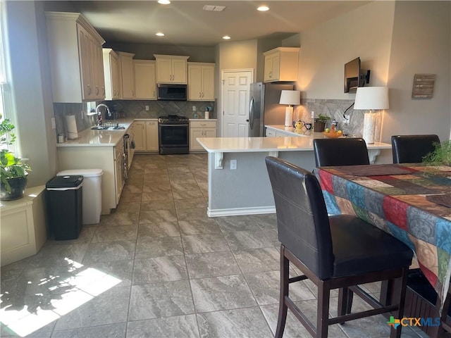 kitchen featuring tasteful backsplash, appliances with stainless steel finishes, kitchen peninsula, and sink