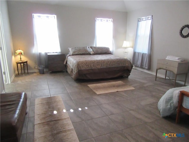 tiled bedroom featuring lofted ceiling and multiple windows