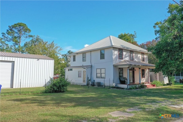 rear view of property featuring an outbuilding, covered porch, and a lawn